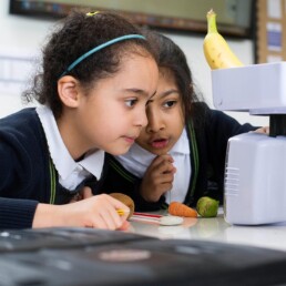 Two girls weighing fruit